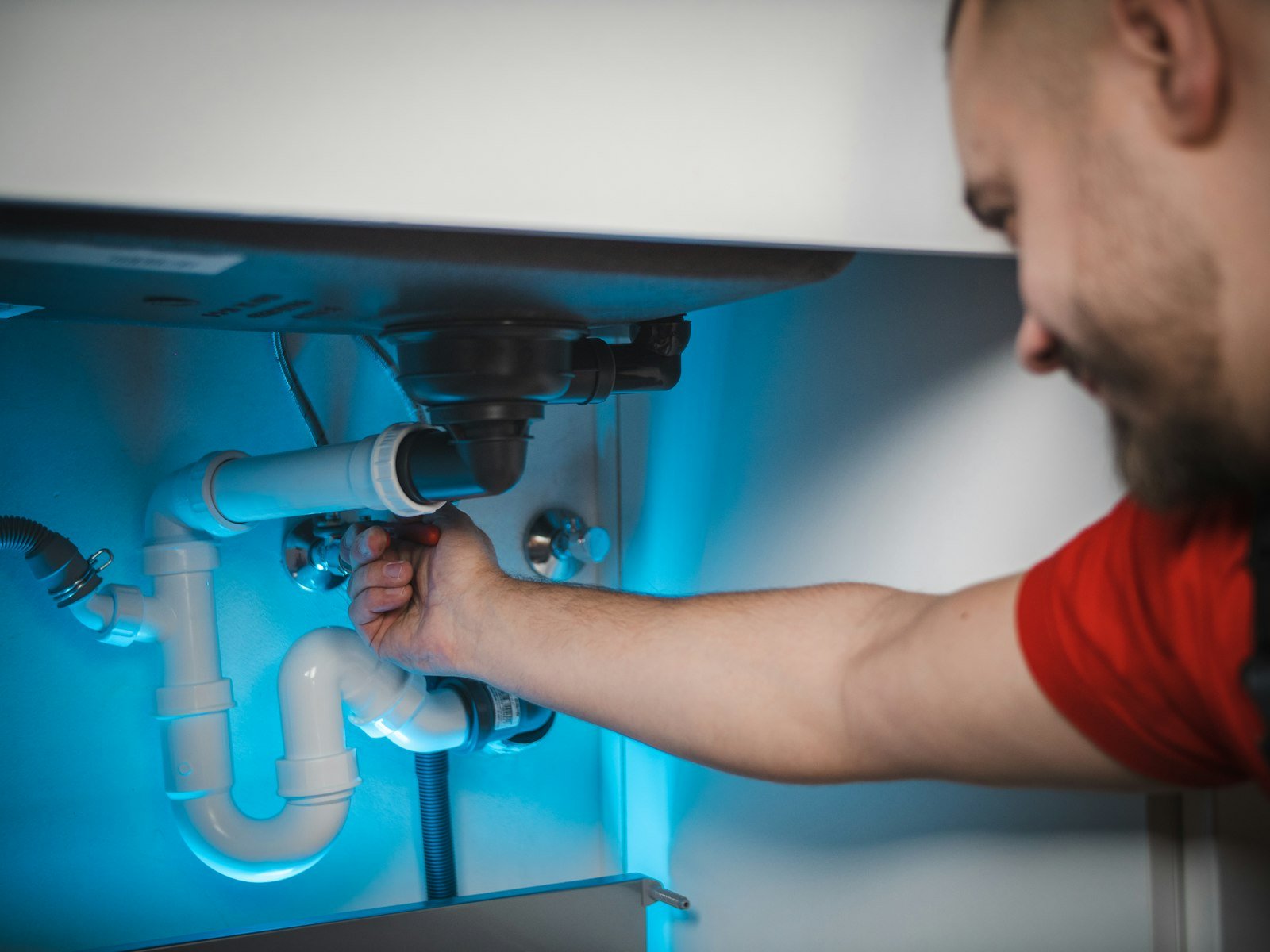 Technician repairing a burst supply pipe opened up inside a wall cavity